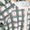 Plaid baby romper on a hanger with a blurred green background