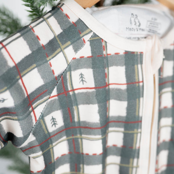 Plaid baby romper on a hanger with a blurred green background