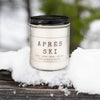 Candle labeled 'Apres Ski' on a snowy surface with a blurred natural background