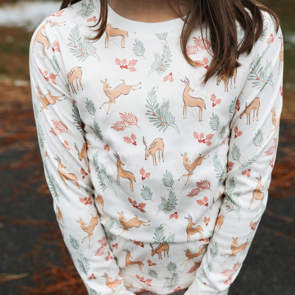 Child wearing a long-sleeve pajama set with deer and floral pattern outdoors.