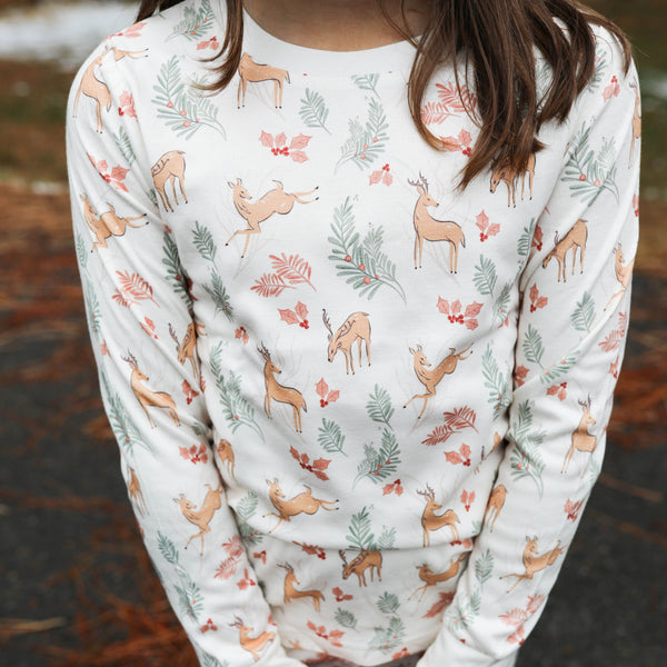 Child wearing a long-sleeve pajama set with deer and floral pattern outdoors.