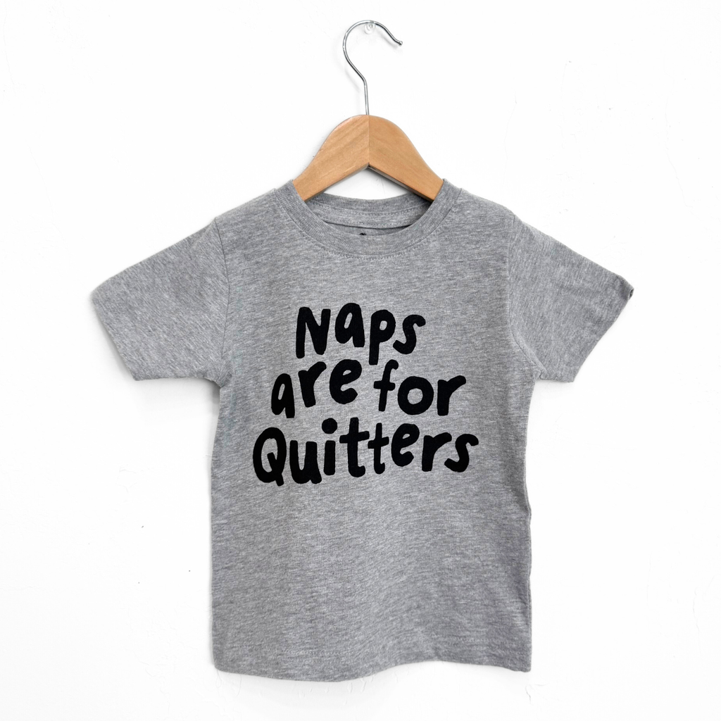 Gray t-shirt with 'Naps are for Quitters' text on a wooden hanger against a white background