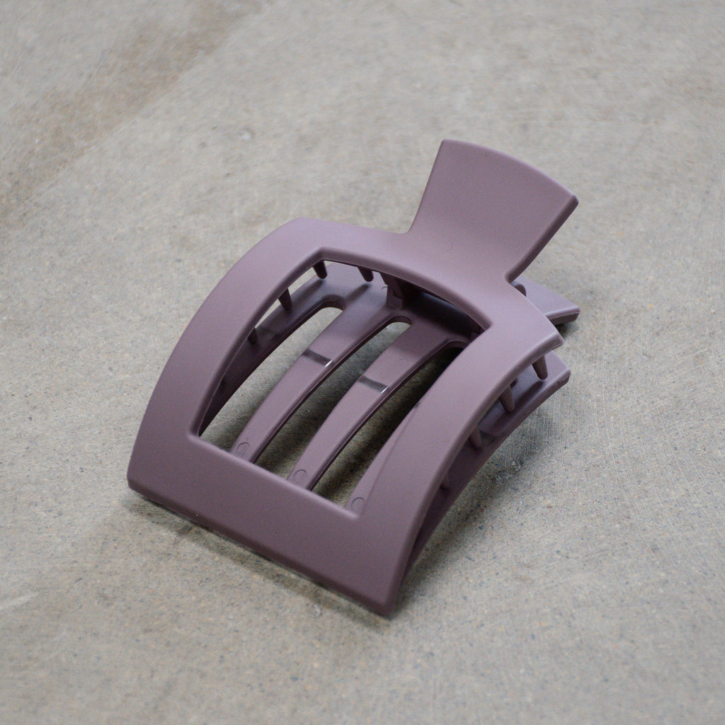 Purple hair clip on a textured beige surface