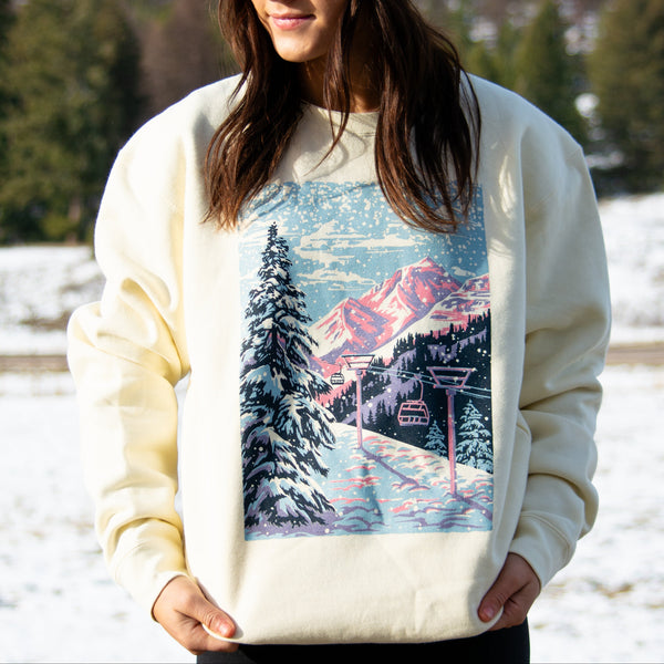 Woman wearing a sweater with a mountain and ski lift design, standing in a snowy landscape.